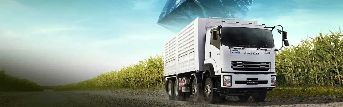 รถบรรทุก ISUZU FYH สีขาวพร้อมคอกสูงบนถนนข้างไร่