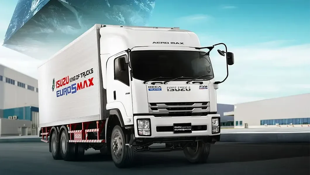 ภาพโฆษณา Isuzu FVM สีขาวพร้อมตู้บรรทุกในลานคลังสินค้า