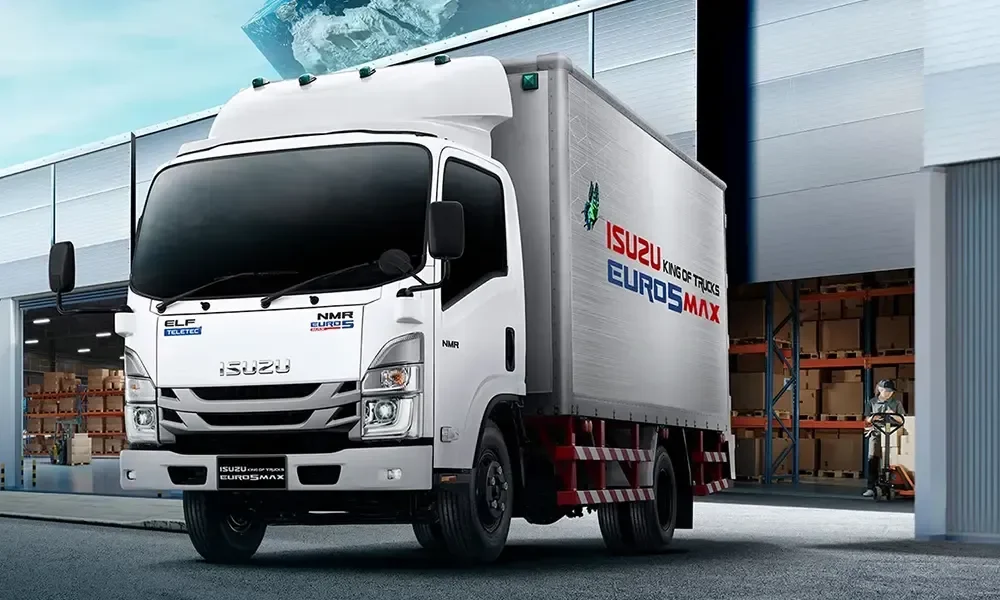 รถบรรทุก Isuzu NMR สีขาวพร้อมตู้บรรทุก จอดด้านหน้าอาคารคลังสินค้า