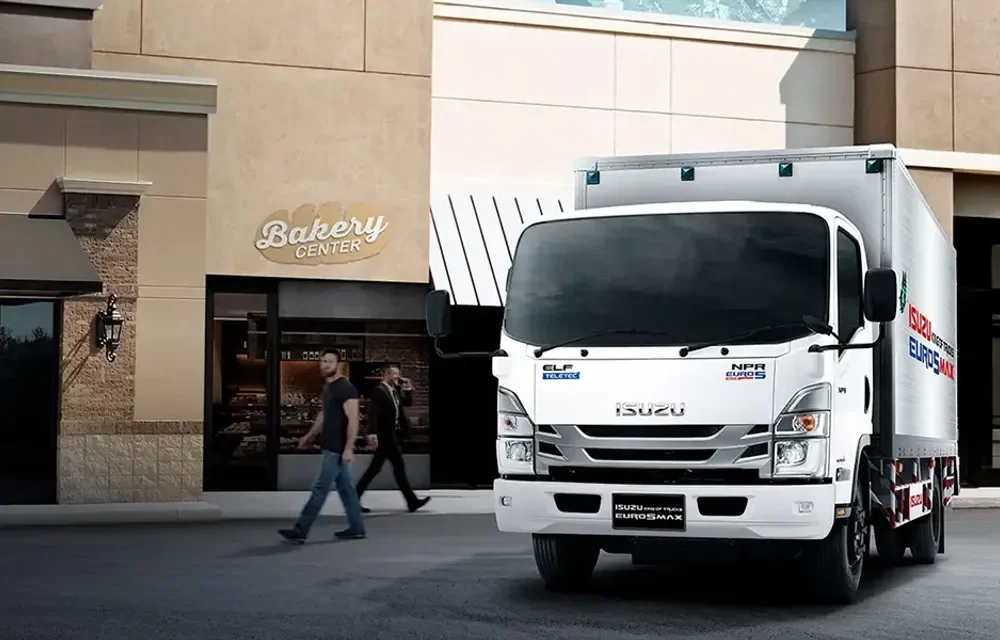 รถบรรทุก Isuzu NPR สีขาวพร้อมตู้บรรทุก จอดหน้าอาคารร้านค้า